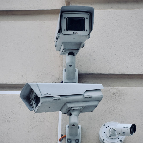 Drei Überwachungskameras unterschiedlicher Modelle sind an einer Wand montiert.