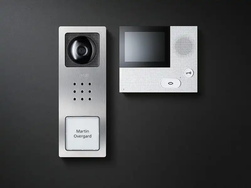 Zwei moderne Türsprechanlagen mit Kamera, Display und Tasten auf schwarzem Hintergrund.